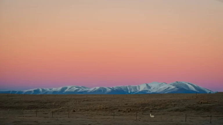 Snow-covered mountains against an orange sherbet sky in Twizel, New Zealand